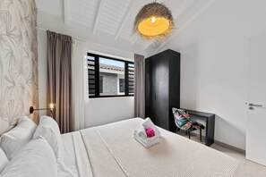 Ein modernes Schlafzimmer mit einem Bett, einem Schreibtisch und einem Fenster mit Rollläden.