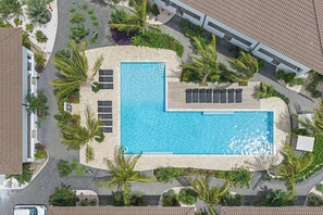 An aerial view of a resort with a swimming pool, lounge chairs, and palm trees. - Sunset Pearl Curaçao | Pool & Free Parking (Mahaai)