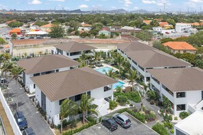 A residential area with modern buildings, a swimming pool, and a clear view of the surrounding landscape. - Sunset Pearl Curaçao | Pool & Free Parking (Mahaai)