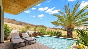 A wooden deck with two lounge chairs and a swimming pool. - Villa Azure Fairways- luxury villa at Bluebay (Bluebay)