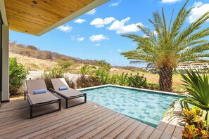 A wooden deck with two lounge chairs and a swimming pool. - Villa Azure Fairways- luxury villa at Bluebay (Bluebay)