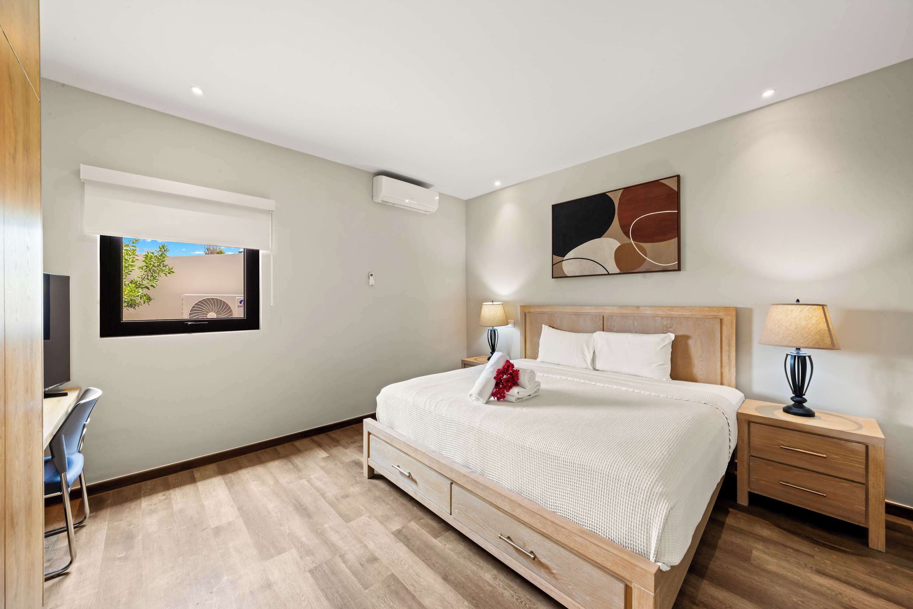 Een moderne slaapkamer met een bed, nachtkastjes, een bureau en een raam met uitzicht.