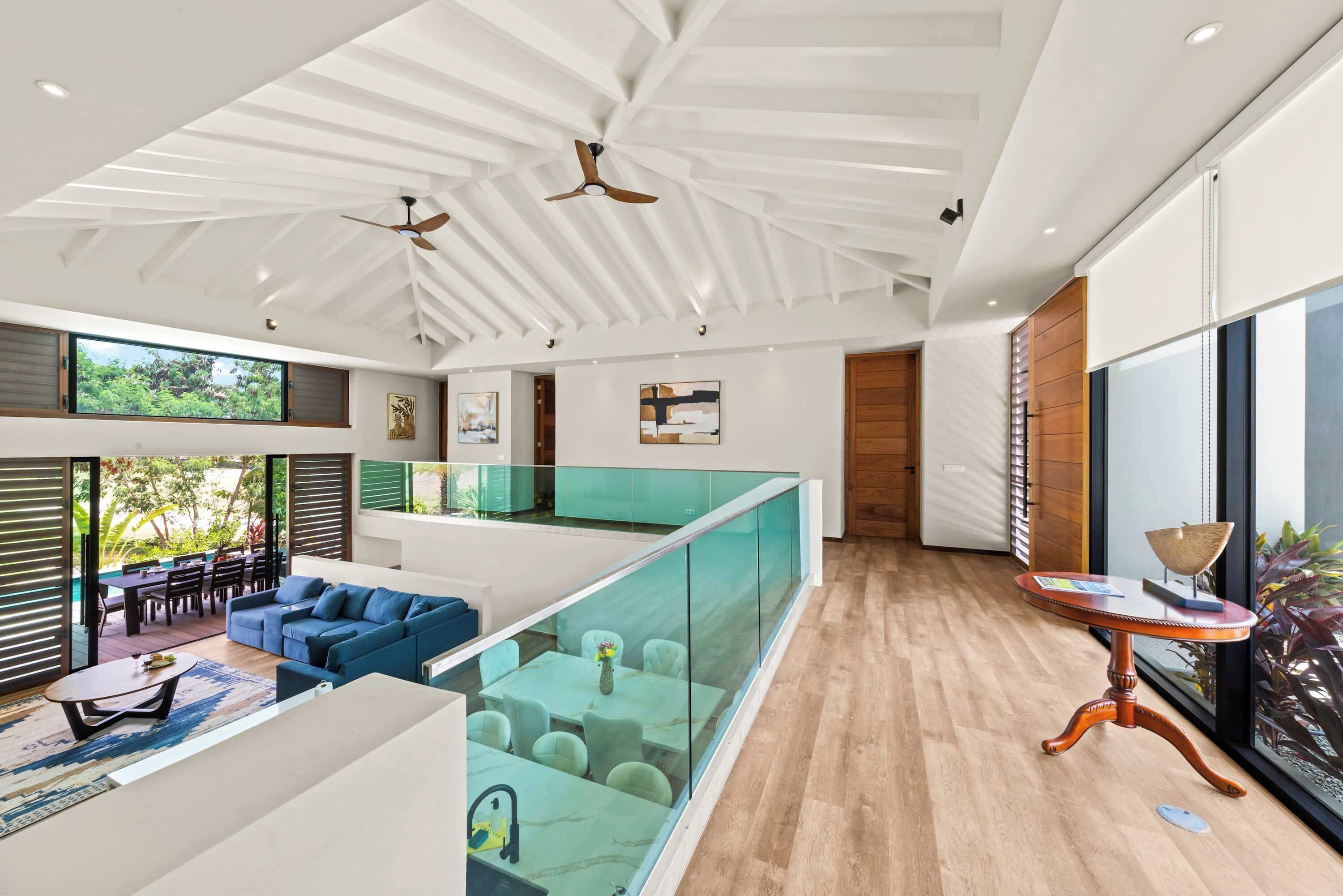 Un intérieur moderne avec une balustrade en verre, un coin repas et un espace salon.