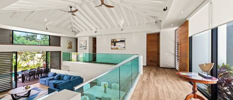 A modern interior with a glass railing, a dining area, and a seating arrangement.