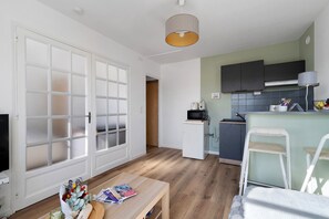 Ett kompakt bostadsutrymme med ett litet kök, en matplats och en tv.