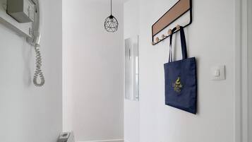 Ein Flur mit Heizkörper, Pendelleuchte und Wandgarderobe mit Tasche.