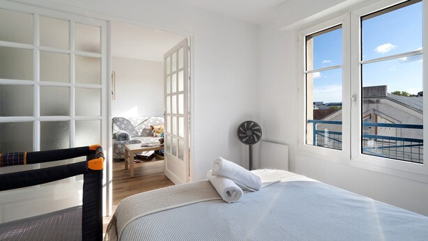 Ein Schlafzimmer mit einem Bett, einem Sessel, einem Tisch und einem Fenster.