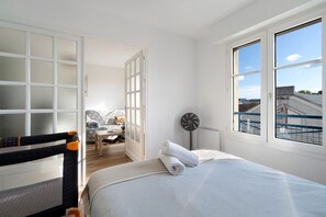 Une chambre à coucher avec un lit, une chaise, une table et une fenêtre.