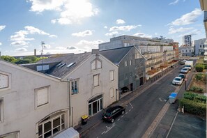 Une vue de rue avec des bâtiments, une voiture garée et un ciel dégagé.