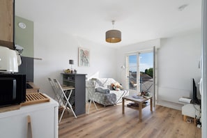 Un espace de vie compact comprenant un coin cuisine, un coin repas et un espace détente avec vue.