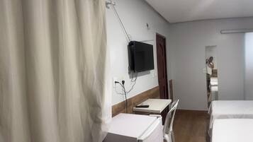 Habitación de hotel con cama, escritorio, silla, televisor montado en la pared y cortina.