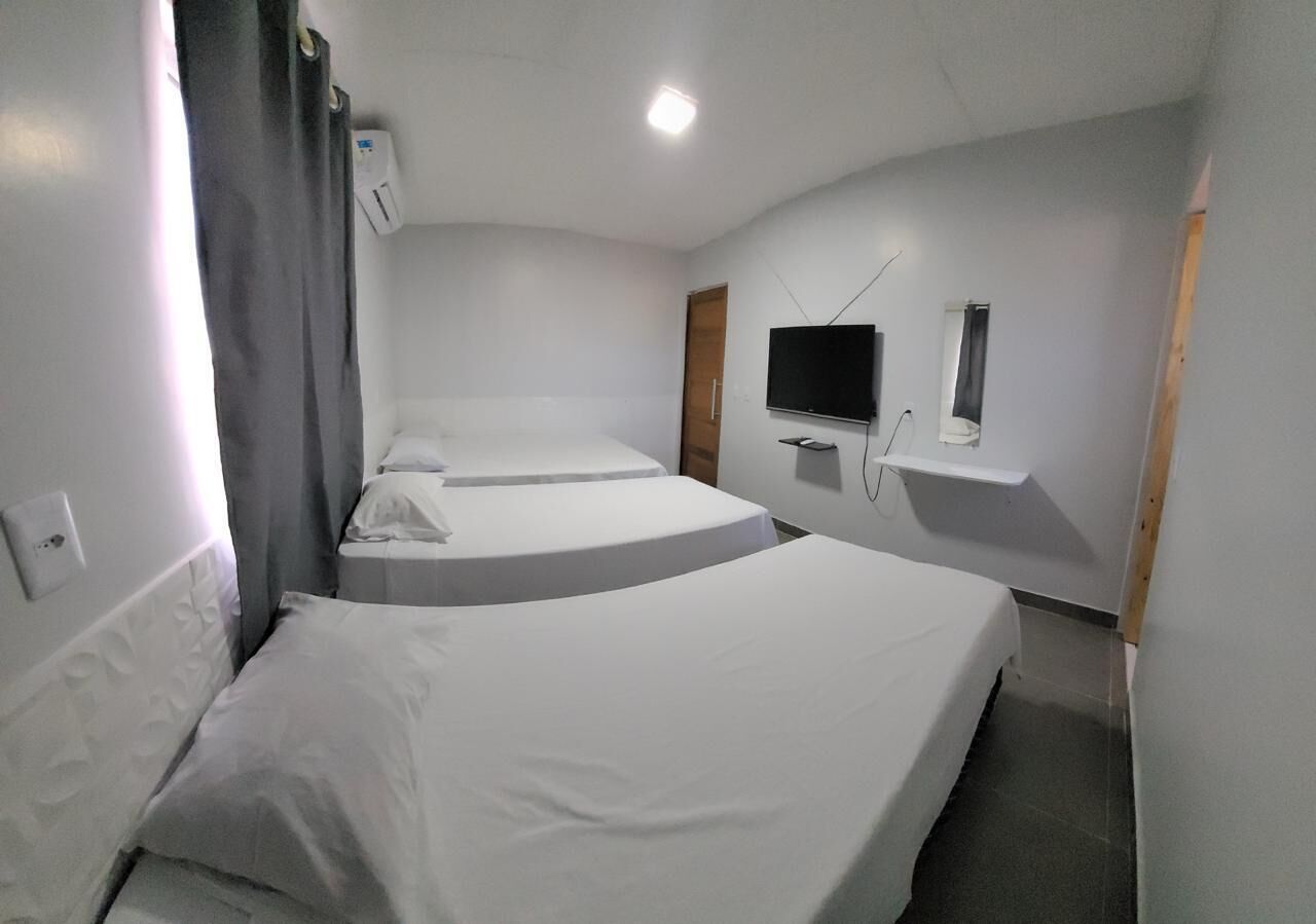 Ein Hotelzimmer mit zwei Betten, einem flachbildfernseher an der Wand und einem kleinen Tisch.