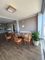 A modern dining area with a wooden table and chairs, a sofa, and a potted plant.