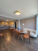 Una sala de estar moderna con una mesa de comedor de madera, sillas y un sofá.