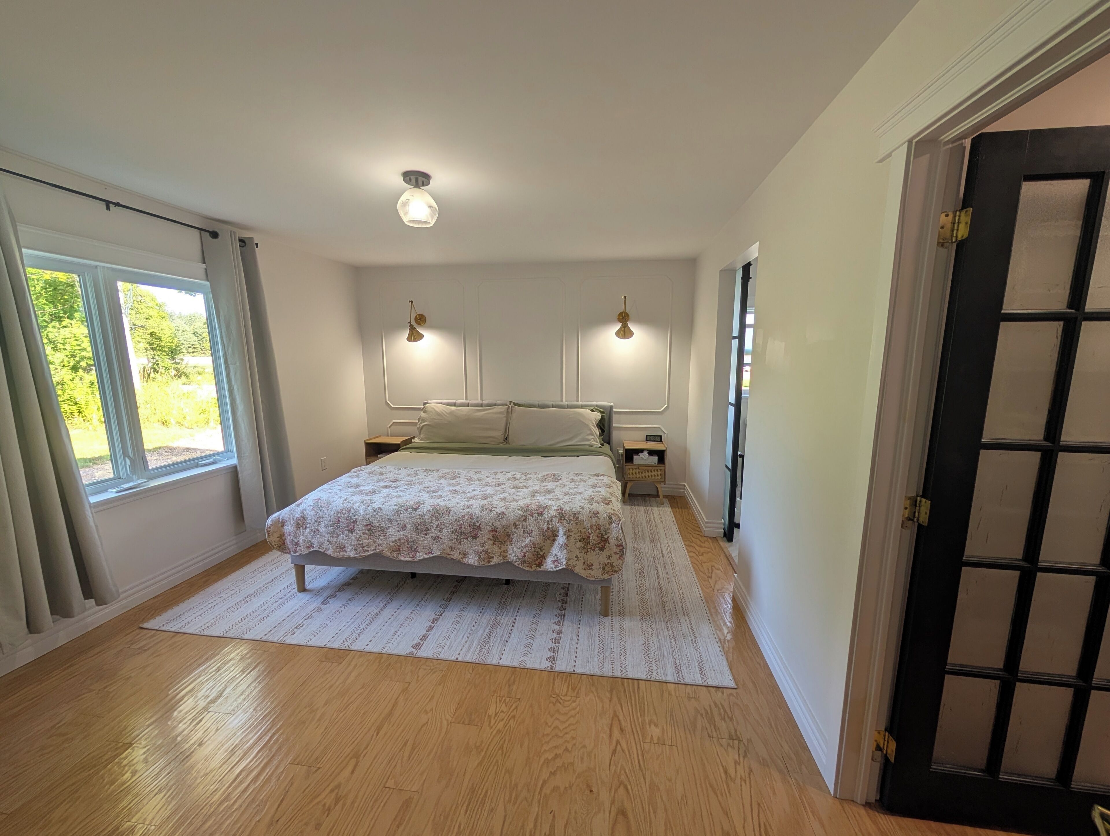 A bedroom with a bed, bedside tables, a window, and a door.