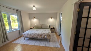 Une chambre à coucher avec un lit, des tables de chevet, une fenêtre et une porte.