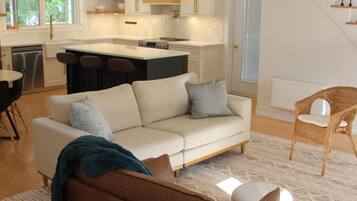 A modern living room with a brown leather sofa, a white sofa, and a patterned rug.