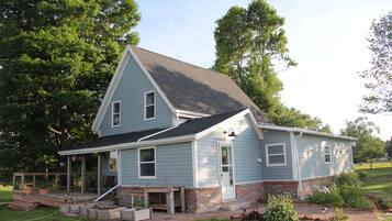 A two-story house with a porch, a front yard, and a brick foundation.