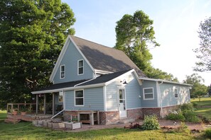 A two-story house with a porch, a front yard, and a brick foundation.