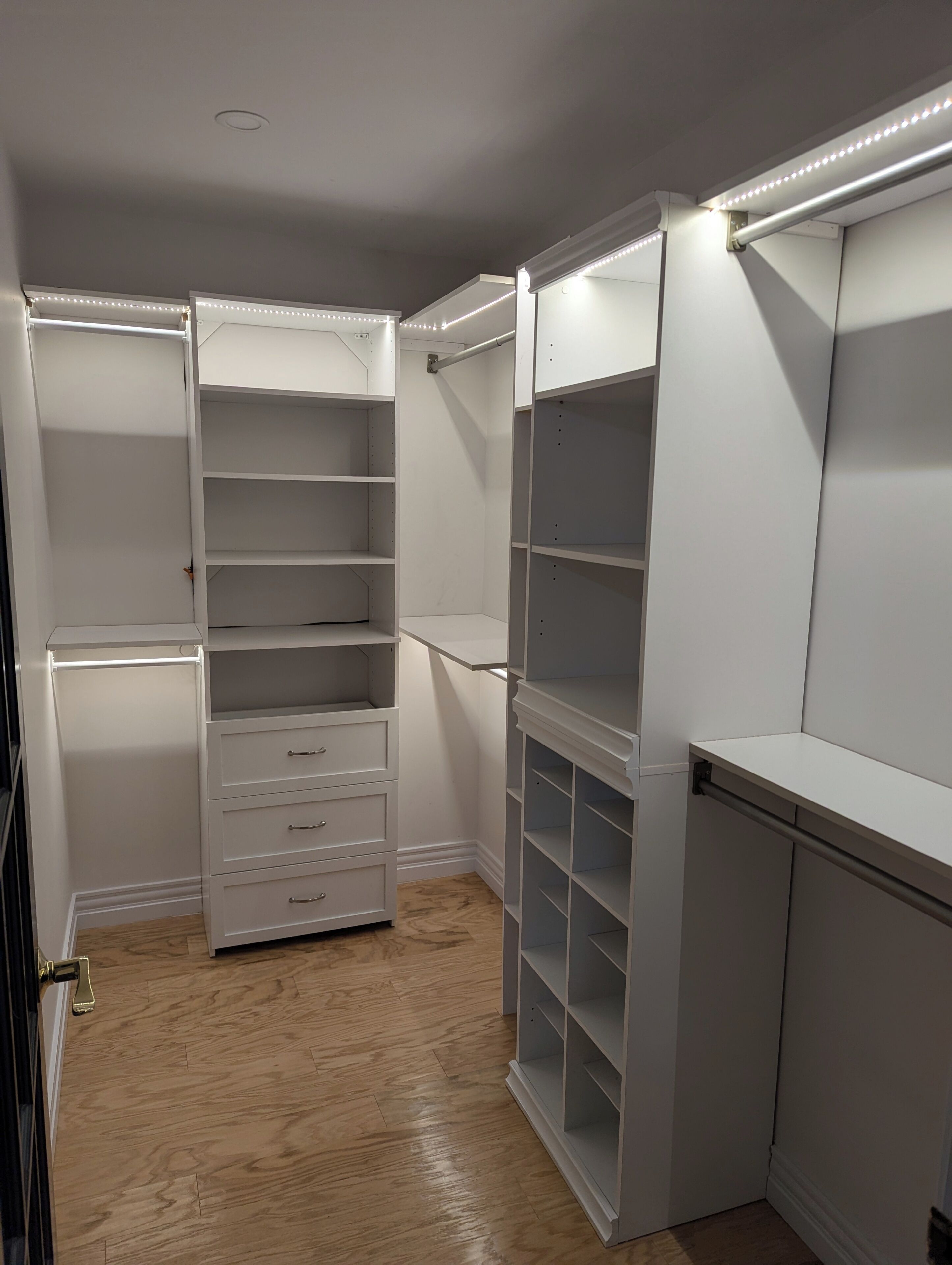 A walk-in closet with open shelving, drawers, and a mirrored section.