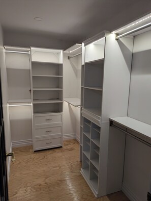 A walk-in closet with open shelving, drawers, and a mirrored section.