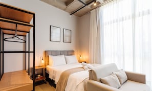 A hotel room with a bed, a sofa, a hanging rack, two framed pictures, and a window with curtains. - Comfortable Studio 750m From Praia de Canas Tps210 (Florianópolis)