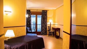 Een hotelkamer met twee bedden, een stoel, een tafel en een balkon met gordijnen.