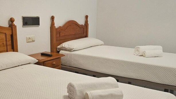 Une chambre d’hôtel avec deux lits simples, chacun recouvert d’une courtepointe blanche à motifs et agrémenté de serviettes blanches pliées.