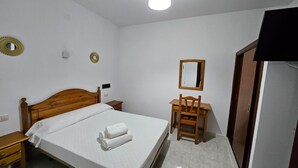 Une chambre à coucher avec un lit en bois, un bureau, une chaise, un miroir et une armoire.