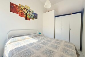 A bedroom with a bed, a wardrobe, and a wall-mounted painting. - SE230 - Marotta, three-room apartment just steps from the beach, with parking space. (Marotta)