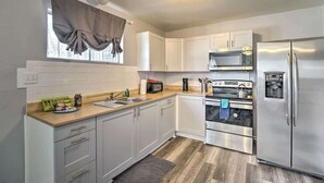 Una cucina moderna con mobili bianchi, elettrodomestici in acciaio inossidabile e una finestra con tende.