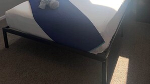 A single bed with a blue and white bedspread, a ceiling fan, a window with blue curtains, and a nightstand with a lamp. - Cozy Guest Retreat for 8 Near The Strip! (North Las Vegas)