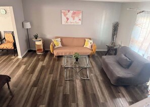 A living room with a sofa, a coffee table, a lamp, and a world map on the wall. - Charming Vegas Getaway | Minutes from The Strip (North Las Vegas)