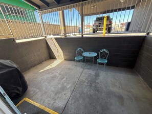 A covered outdoor area with a concrete floor, metal chairs, and a table. - Charming Vegas Getaway | Minutes from The Strip (North Las Vegas)