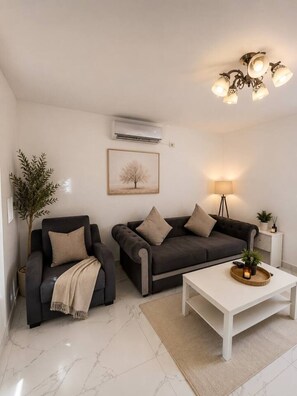 Ein Wohnzimmer mit Sofa, Sessel, Couchtisch und Lampe.