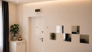 A modern living room with a sofa, a cabinet, and a door. - Deluxe Two-Bedroom Apartment with Balcony (Bucharest)