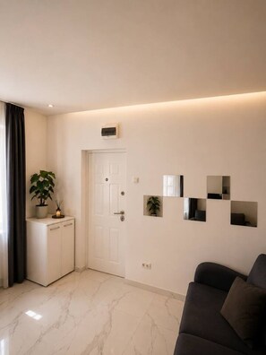A modern living room with a sofa, a cabinet, and a door. - Deluxe Two-Bedroom Apartment with Balcony (Bucharest)