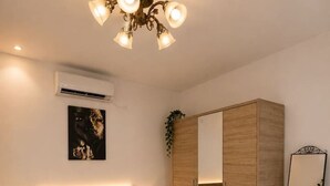 A bedroom with a bed, bedside tables, a wardrobe, a mirror, and a ceiling light fixture. - Deluxe Two-Bedroom Apartment with Balcony (Bucharest)