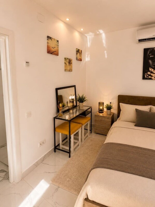 A bedroom with a bed, bedside table, dresser, and a desk with a mirror. - Deluxe Two-Bedroom Apartment with Balcony (Bucharest)