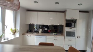 Una cocina compacta con armarios blancos, microondas y lavavajillas.