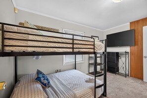 A bunk bed room with a desk and a television.