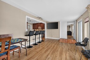 A modern kitchen with a dining area, a flat-screen TV, and a hallway leading to other rooms. - Best of Grandview! 7 Beds, waterfront & dock! (Hampton)