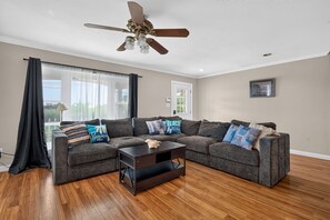 A living room with a sectional sofa, a coffee table, and a ceiling fan.