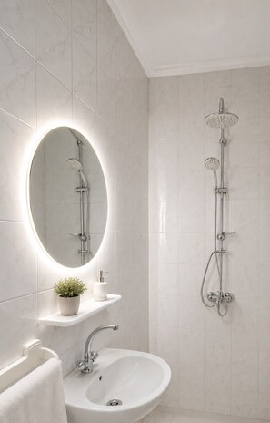 Een moderne badkamer met een ronde spiegel, een wastafel en een douche.