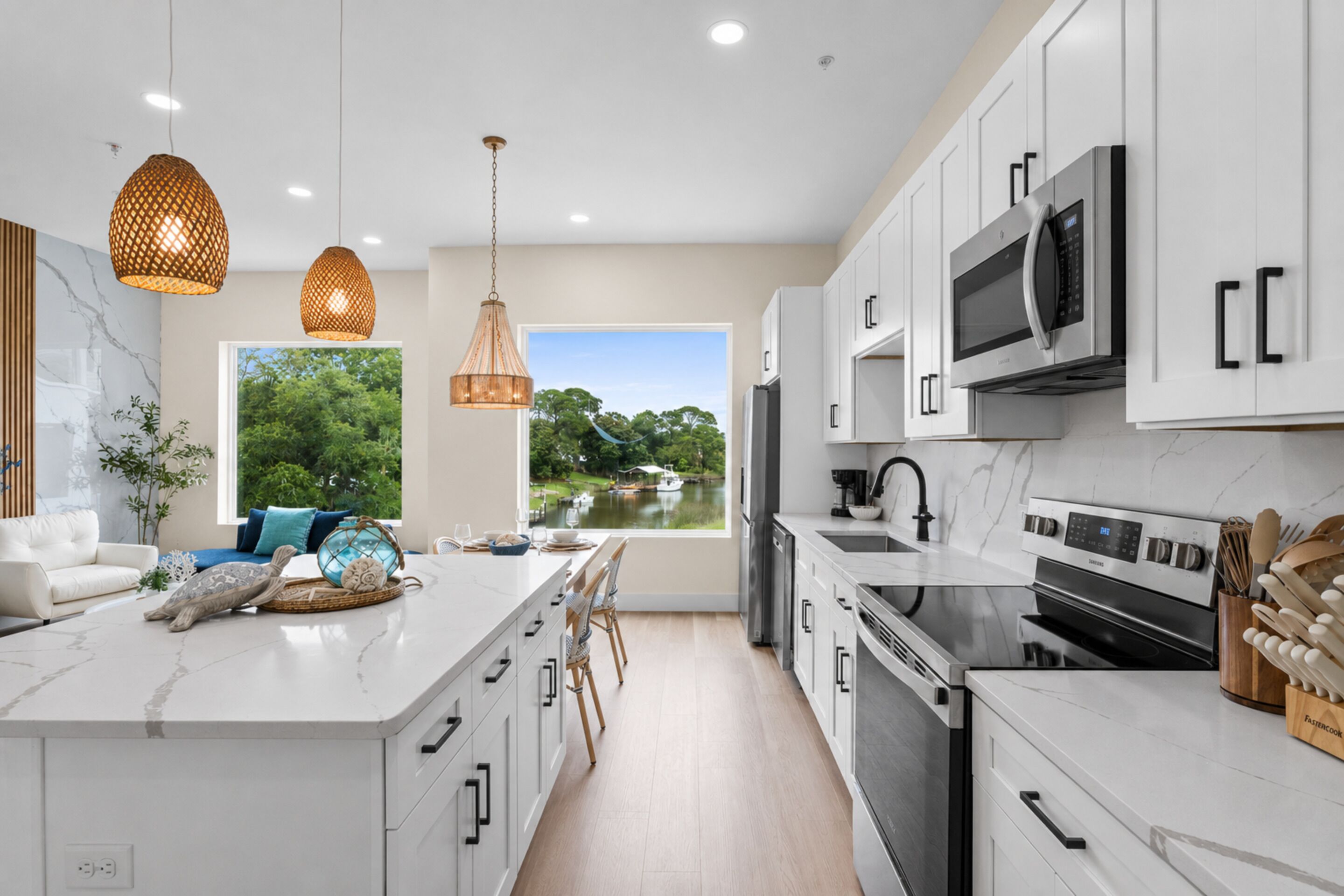 A modern kitchen with white cabinetry, stainless steel appliances, and a large island with seating.