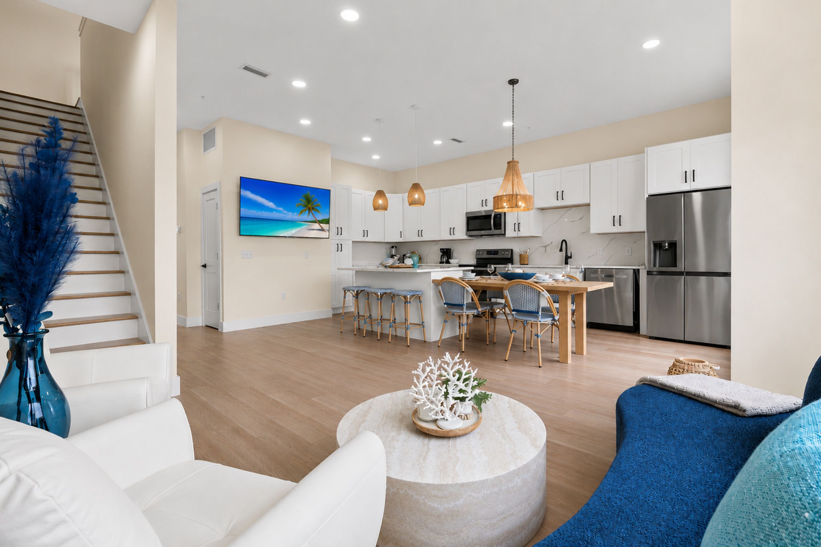 A modern kitchen with white cabinets, stainless steel appliances, and a central island with bar stools.