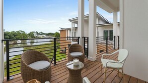 A balcony with wicker furniture, a view of a river, and a building in the background. - 3002 Blue Lagoon C (Panama City Beach)
