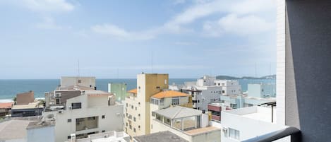 A coastal cityscape with buildings, a clear sky, and the sea in the background.