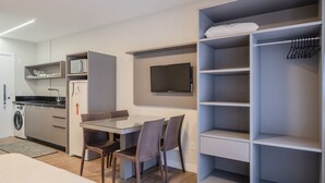 A compact kitchenette with a microwave, refrigerator, and washing machine. There is a dining area with a table and chairs. A television is mounted on the wall. - Studio w/ Pool & BBQ 300m From Sea Vfr505 (Bombinhas)