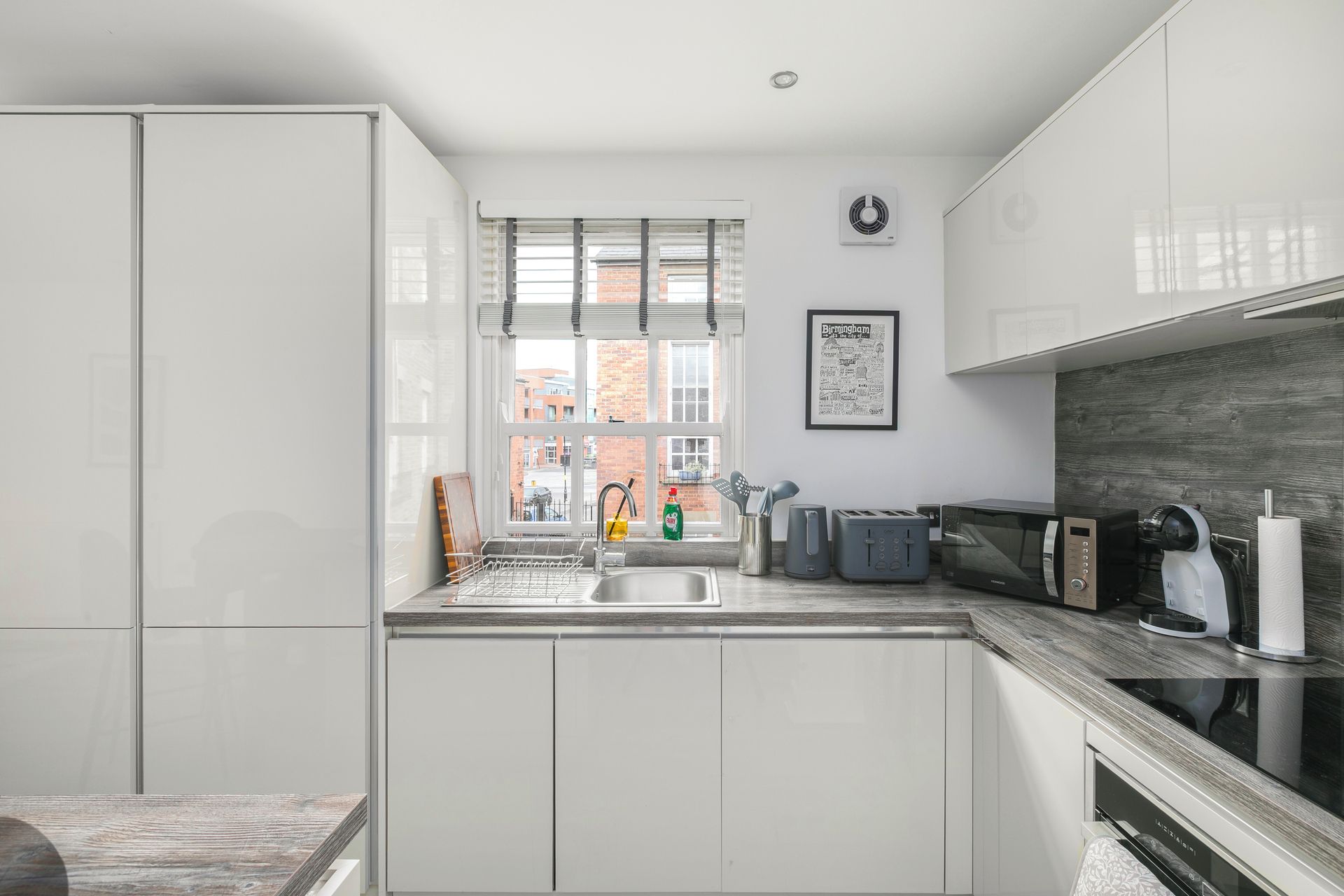 A modern kitchen with white cabinetry, a built-in microwave, and a view of the city.